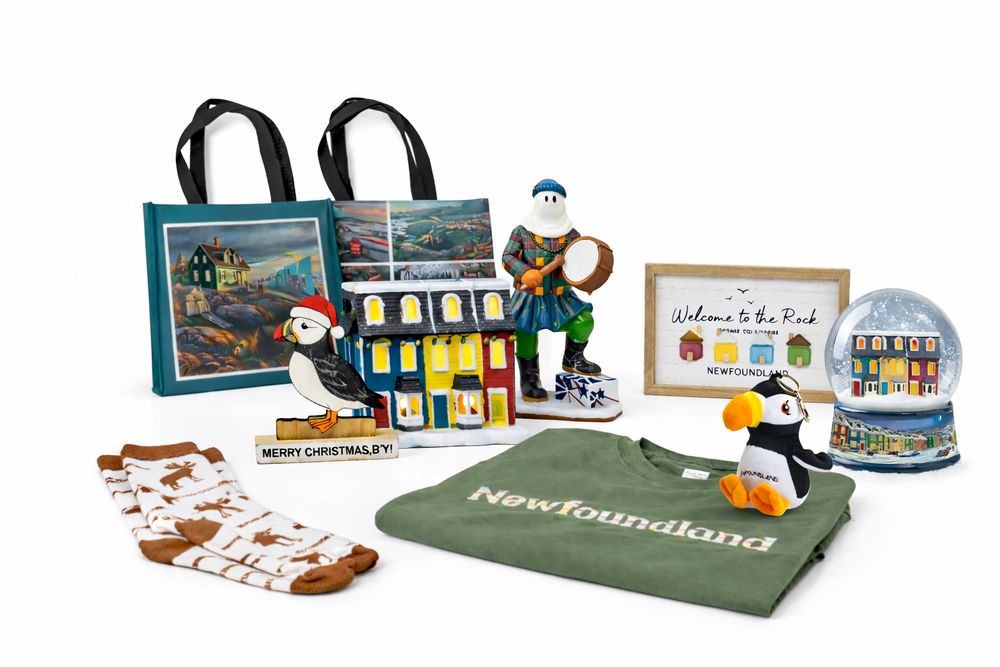 Islandwide giftware: printed tote bags, a puffin in a Santa hat, a lit row-house ornament, a mummer figurine, a Welcome to the Rock sign, a snow globe, moose socks and a green Newfoundland tee